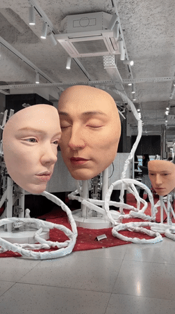 Realistic human face sculptures displayed in Paris indoor venue