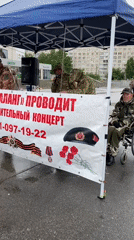 Group gathers under canopy for microphone event in rainy Petersburg