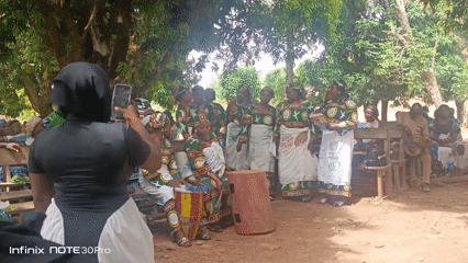 Women in matching outfits gather with song sheets in Akwanga