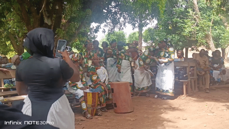 Women in matching outfits gather with song sheets in Akwanga