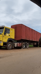 Yellow-red truck travels rural road near Vom, Nigeria