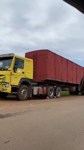 Yellow-red truck travels rural road near Vom, Nigeria