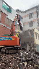 Orange excavator demolishes building in Thuận An, Vietnam