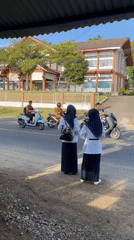 Students observe roadside traffic, woman prepares food stall in Lhokseumawe
