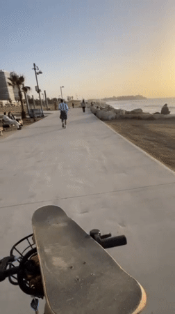 Cyclist tours Tel Aviv waterfront during Mediterranean sunset