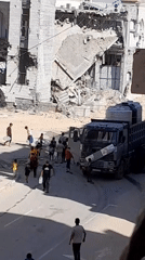 Water distribution at a truck amid heavy urban damage in al-Qarara