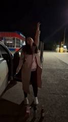 Woman stands by open car door at night in Chaikovsky