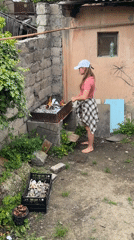 Woman tends backyard grill in Tbilisi yard