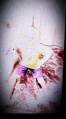 The video appears to be a recording of a person, possibly a child, dancing or posing in front of a camera. The subject is wearing a light-colored shirt and purple shorts. The background is somewhat abstract with vertical pink lines and textured flooring. The lighting is bright, suggesting an indoor setting. There is no visible text in the video. The overall mood is unclear due to the abstract nature of the visuals and the lack of context. The footage has a grainy quality, and the colors are somewhat muted and distorted. The setting does not provide any specific clues about the time of day, weather, or precise location beyond the general suggestion of an indoor space.