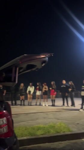 Young adults gather around car sound system in Arica