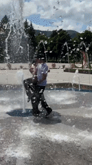 Young men play in fountain during sunny day in Karachayevsk