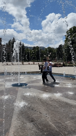 Young men play in fountain during sunny day in Karachayevsk