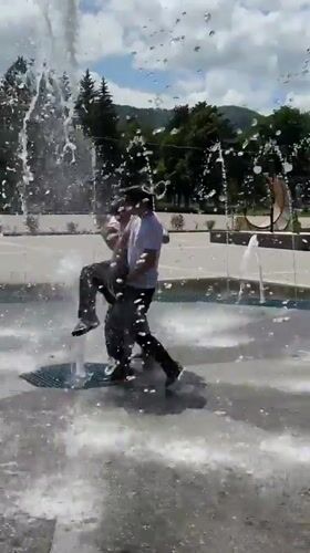 Young men play in fountain during sunny day in Karachayevsk