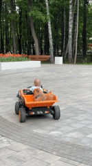 Child drives toy truck with dog passenger in Khimki park