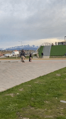 Skateboarder attempts jump trick in Ushuaia park on cloudy day