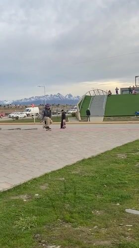 Skateboarder attempts jump trick in Ushuaia park on cloudy day