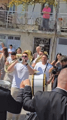 Street brass band plays at an outdoor wedding procession