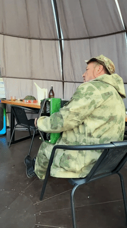 Camouflaged musician plays accordion in Russian gazebo