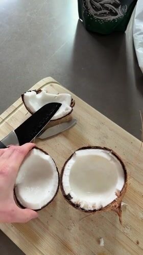 Fresh coconut cracked open on a cutting board in Fife