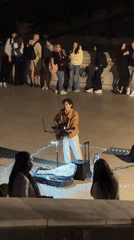 Street musician performs guitar near illuminated Eiffel Tower