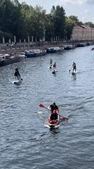 Costumed paddleboarders cruise a Saint Petersburg canal in summer.