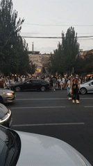 Busy urban street with crowds, parked EVs, and street-level details