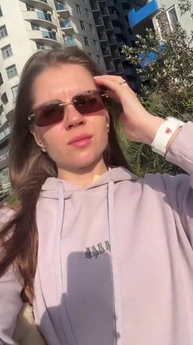 Woman poses for selfies on Batumi street amid urban scenery