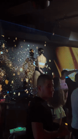 Club platform dancing with gold and red particle projection backdrop