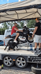 Motorcycle testing and car display at outdoor automotive event