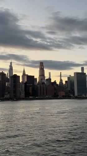 Nighttime skyline view captured across choppy East River