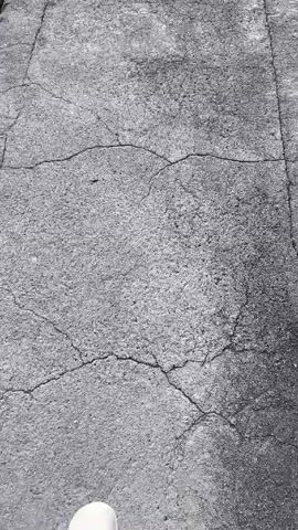 The video shows a concrete platform extending into a body of water. The platform has several cracks running across its surface.  The water reflects the sky, creating a blurry mirror image of clouds and perhaps a mountain or hillside.