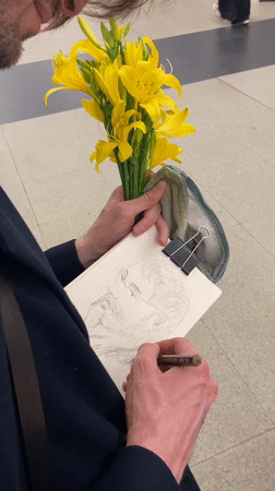 Artist sketches portrait while holding yellow flowers in Moscow