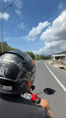 Helmeted rider travels red scooter on Vietnam road