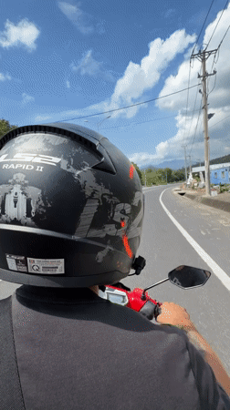 Helmeted rider travels red scooter on Vietnam road