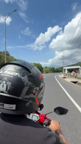 Helmeted rider travels red scooter on Vietnam road