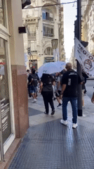 Demonstrators march through Buenos Aires Microcentro with flags, umbrellas