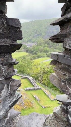 Tourist explores historic stone ruins and quarry landscapes in Llanberis