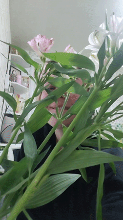 Person peers through flower bouquet in Noviy, Russia