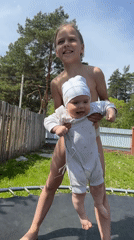Girl and baby play on trampoline in Russian backyard