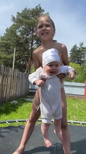 Girl and baby play on trampoline in Russian backyard