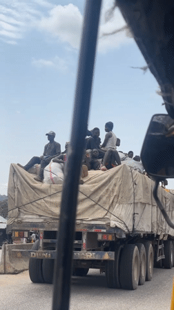Passengers ride atop semi-truck cargo bed in Lokoja
