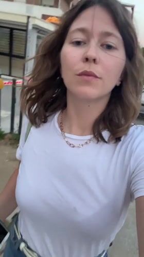 Woman films selfie video in Podgorica street during twilight