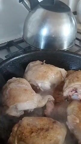 The video shows chicken pieces being pan-fried. The camera is positioned close to a black frying pan containing several pieces of chicken. The chicken appears to be browning and releasing steam as it cooks. In the background, a shiny metal kettle is visible on a stovetop. The setting appears to be a kitchen. There is no visible text in the video. The activity is cooking. The time of day and weather are not discernible from the footage. The location context provided is Horenka, Ukraine, but there are no specific visual cues in the video to confirm this location. The overall mood is neutral, focusing on the culinary activity.