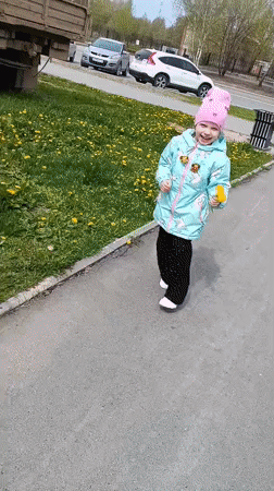 Child plays outdoors, picks dandelions in Tobolsk morning