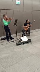 Street musicians perform near a city with underground parking nearby