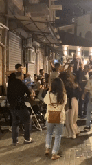 Young adults dance in Tel Aviv alleyway during nighttime gathering