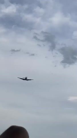 This media file captures a single-engine turboprop aircraft in flight. The plane is viewed from below, ascending against a backdrop of a partially cloudy sky. The clouds are varied, ranging from wispy formations to denser, darker patches, suggesting a dynamic weather pattern. The sky transitions from a lighter, overcast tone at the beginning of the clip to a clearer, deeper blue as the video progresses.

The aircraft itself is a prominent subject, its silhouette and details becoming more defined as it flies closer to the camera. The plane has a high wing configuration, a single propeller at the front, and a T-tail. In the latter frames, visible text on the underside of the aircraft's fuselage can be partially discerned, reading "HB-FDK" and "PC-12-NG". This indicates the aircraft is a Pilatus PC-12.

The activity is straightforward: an airplane in flight. The scene is set in the open sky, with no discernible ground features except for a sliver of what appears to be a person's head or shoulder at the very bottom of the initial frame, suggesting the recording was made from the ground. The time of day is not explicitly stated but the lighting suggests daytime, likely late morning or afternoon given the clarity of the blue sky towards the end. There are no strong emotional cues conveyed; the media is objective and focused on the aerial subject. The location context of Milvignes, Switzerland, is provided externally.