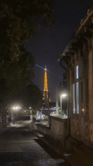 Eiffel Tower glowing at night, seen from across Paris
