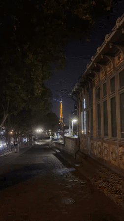 Eiffel Tower glowing at night, seen from across Paris