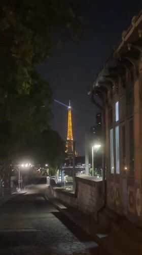 Eiffel Tower glowing at night, seen from across Paris